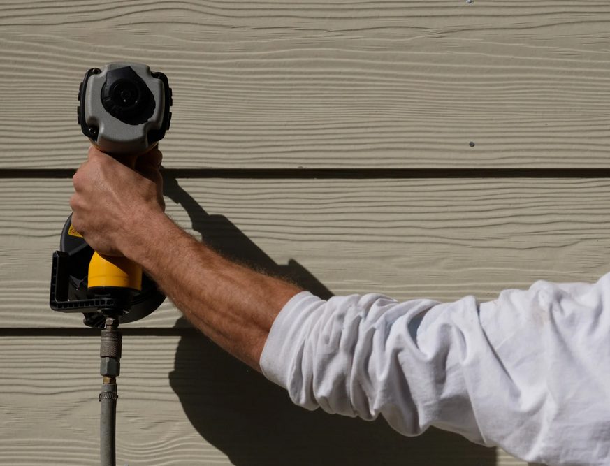 Installer fastening fiber cement siding on a home exterior